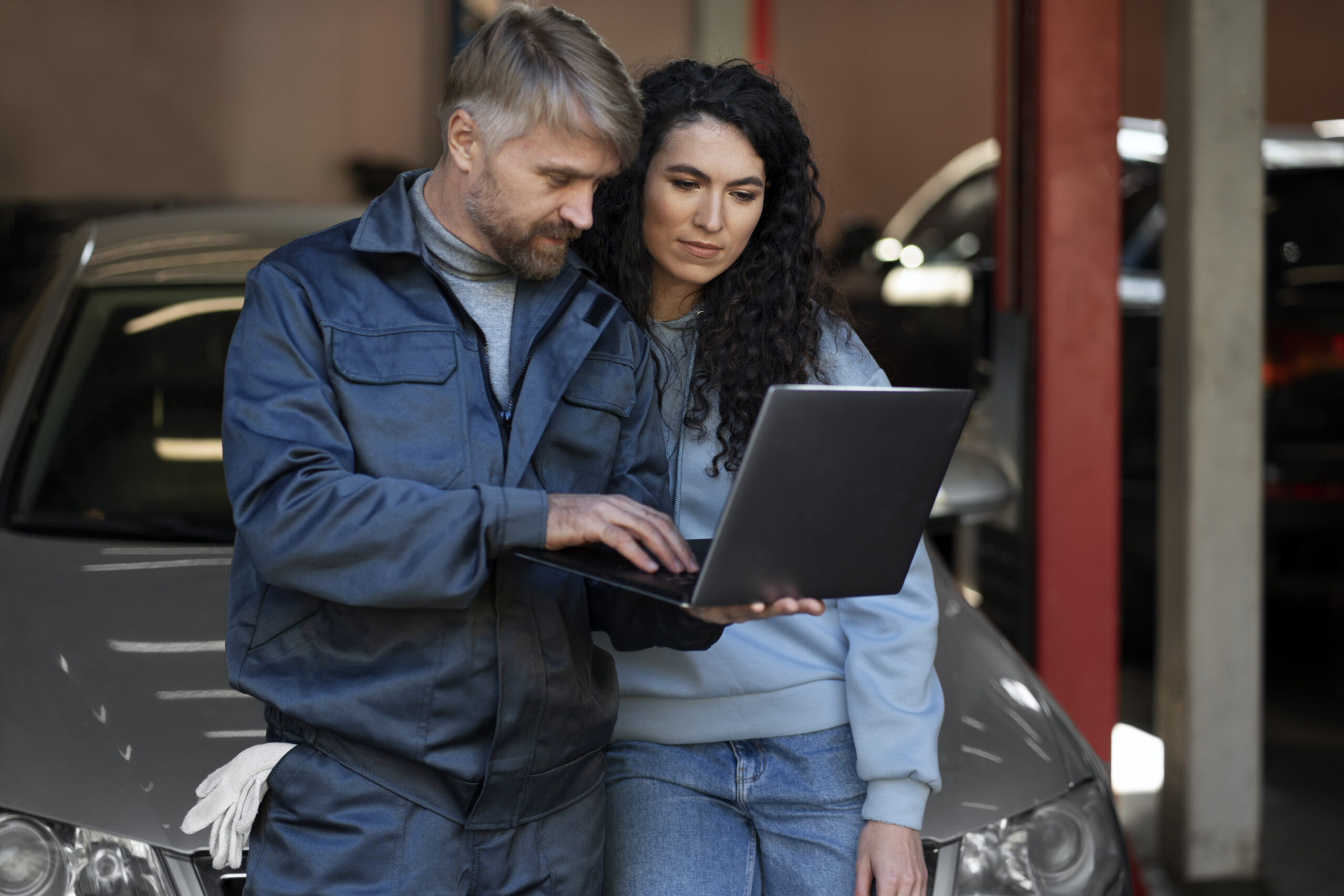 Man and woman looking at a laptop in front of a car